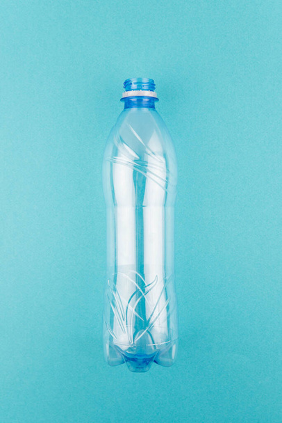 Порожня пластикова пляшка на синьому фоні з копіюванням простору для тексту. Концепція переробки пластику та екології. Плоский прошарок, вид зверху
 - Фото, зображення
