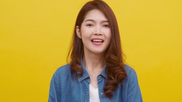 Portrait of young Asian lady with positive expression, excited screaming, dressed in casual clothing and looking at the camera over yellow background. Happy adorable glad woman rejoices success. - Footage, Video
