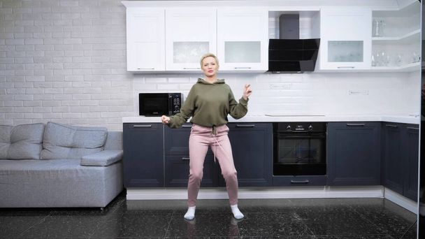 стильна молода жінка танцює вдома на кухні
 - Фото, зображення