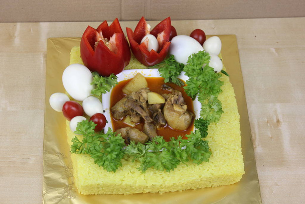 Prato malaio com arroz amarelo glutinoso, legumes e carne
 - Foto, Imagem