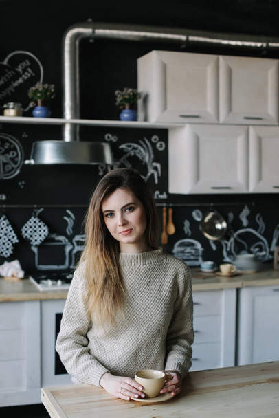 A girl drinking coffee in the kitchen at home. Young woman holding cup of coffee.  Girl drinking beverage in cafe. Good morning.  - Fotografie, Obrázek