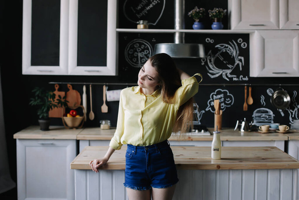A girl drinking coffee in the kitchen at home. Young woman holding cup of coffee.  Girl drinking beverage in cafe. Good morning.  - Foto, afbeelding