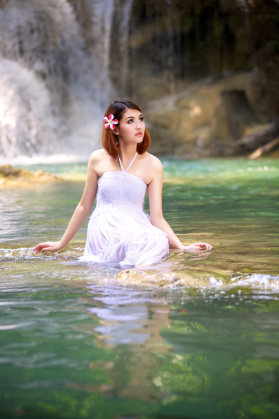 Jovem relaxante na corrente de água perto da cachoeira
 - Foto, Imagem