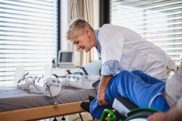 A healthcare worker and paralysed senior patient in hospital. - Fotografie, Obrázek