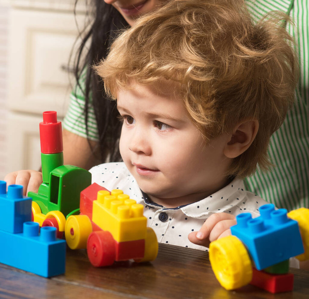 Baby boy looks at train made out of construction blocks. - Foto, Bild