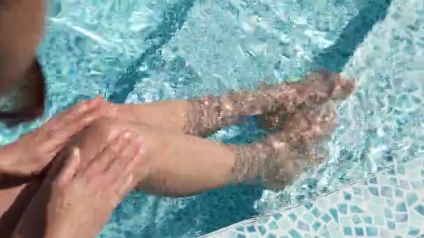 top view legs of unrecognizable woman relaxing in swimming pool at luxury hotel spa - Video, Çekim