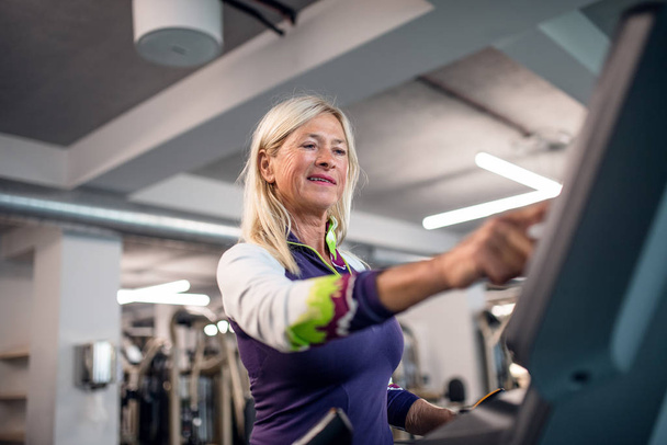 A senior woman in gym doing cardio work out exercise. - Foto, afbeelding
