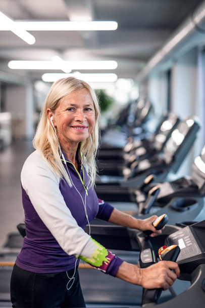 A senior woman in gym doing cardio work out exercise. - Zdjęcie, obraz