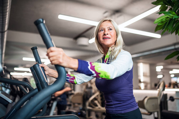 A senior woman in gym doing cardio work out exercise. - Photo, image