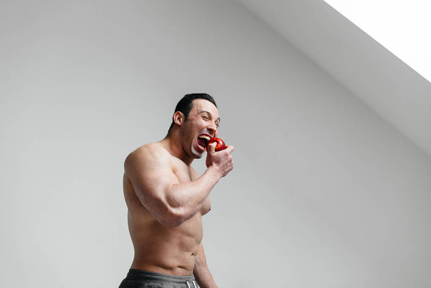 Sportowy seksowny facet jedzący owoce na białym tle. Dieta. Zdrowa dieta - Zdjęcie, obraz