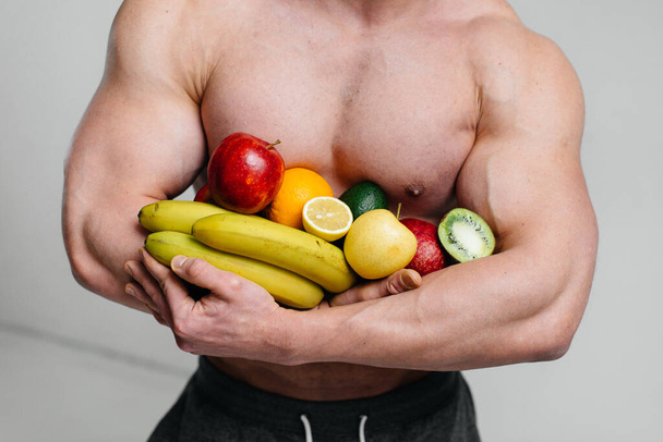 Sporty sexy guy posing on a white background with bright fruits. Diet. Healthy diet - Foto, Imagem