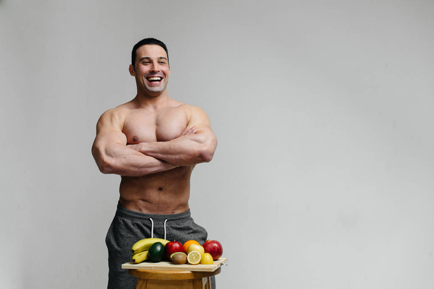 Hombre vegano sexy con un torso desnudo posando en el estudio junto a la fruta. Dieta. Dieta saludable - Foto, Imagen