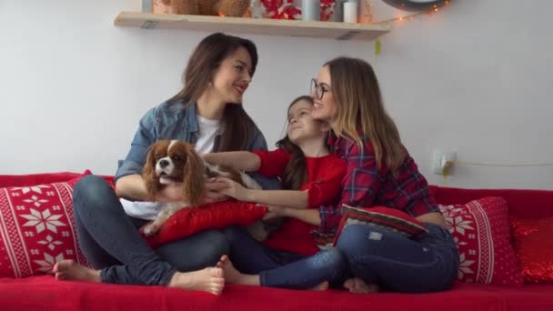 Twee gelukkige vrouwen en klein meisje met hond knuffelen op het bed - Video