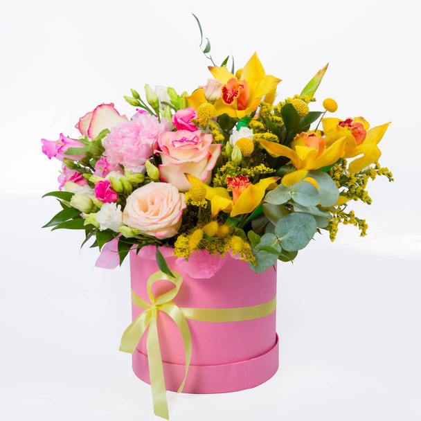 Flower arrangement in a hat box, a pot of pink for a girl on a gift with roses, orchids. Bouquet of beautiful flowers in the cylinder pink box isolated on white background - Фото, изображение