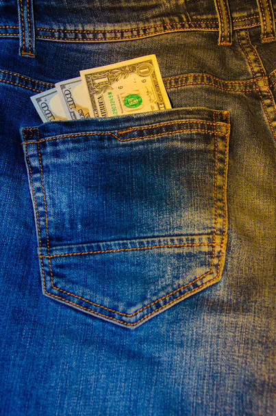 American banknotes in jeans pocket. A note in denominations of $ 100 peeps, stick out from the back, the foremost pants pocket. Money falls out of pocket. Flare effect. View from different angles - Photo, Image
