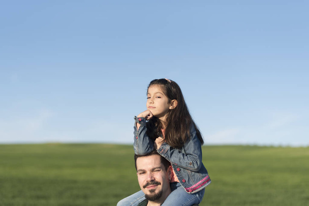 Modern father with daughter on shoulders in spring field - Foto, immagini