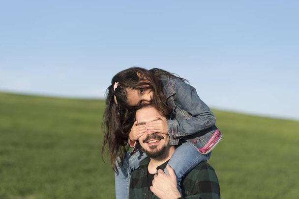 Modern father with daughter on shoulders in spring field - Φωτογραφία, εικόνα