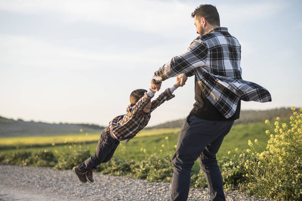 Spinning father grabbing son with arms, spinning - Foto, Bild