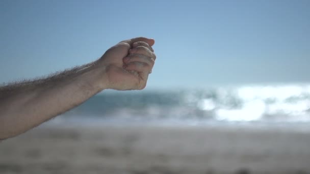 Zblízka záběr na blízký muž ruku na pláži, drží plážový písek a pomalu otevřít - Záběry, video