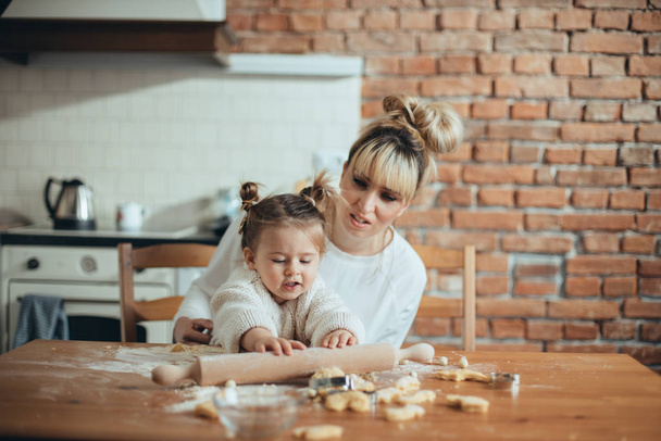 Mother and daughter baking cookies in their kitchen - Foto, afbeelding