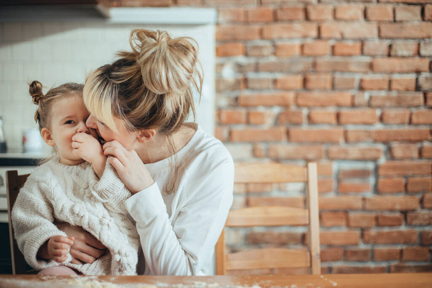 Mother and daughter baking cookies and hugging - Фото, зображення