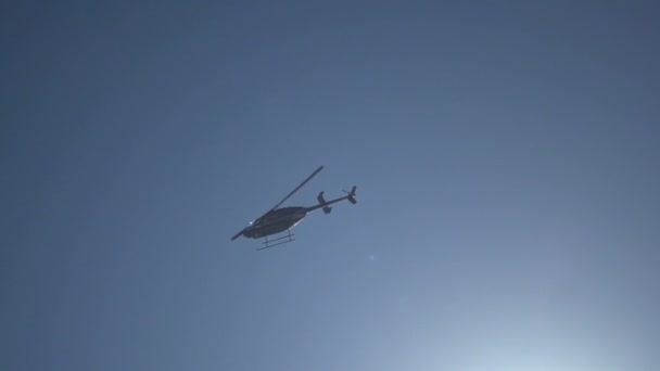 Helikopter helikopter a kék égen, fénysugarakkal. Lassú mozgás gyors záridő - Felvétel, videó