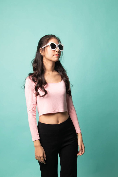 Retrato de una hermosa joven asiática en gafas de sol sobre fondo cian
 - Foto, Imagen
