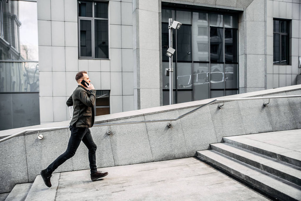mies kannettavan kanssa juoksee portaita ylös toimistoon
 - Valokuva, kuva