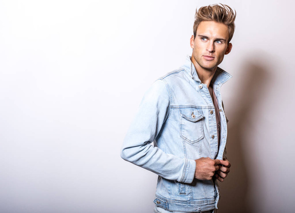 Handsome young man in jeans jacket pose in studio. - Valokuva, kuva