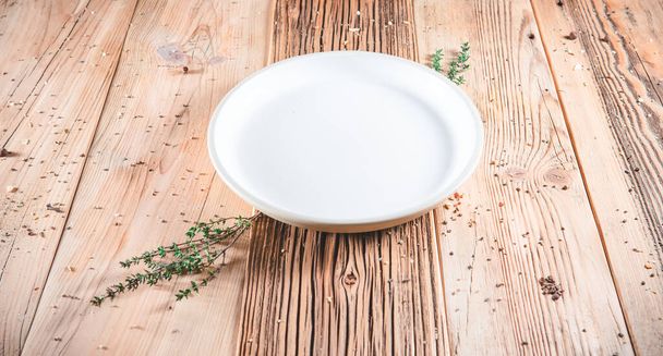 Blank clean white plate on wooden table. Food invitation. Ready to serve and cook fresh meal. Copy empty space  - Фото, зображення