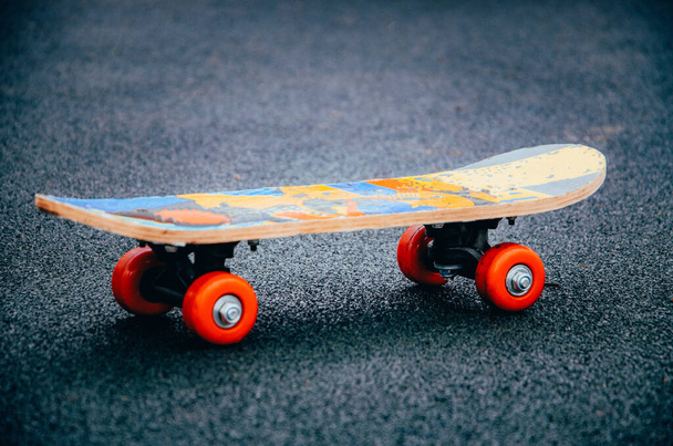 Skateboard auf schwarzem Hintergrund mit knallroten Rädern. Schlittschuhseite und -winkel. Skateboard für Kinder und Erwachsene. Sport. Skateboard auf dem Bürgersteig - Foto, Bild