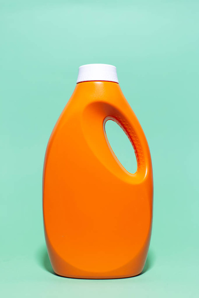Primer plano de la botella de detergente naranja con maqueta sobre el fondo de aqua menthe color
. - Foto, Imagen