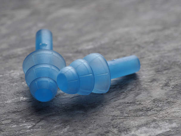 Siliconen blauwe oordoppen om op een grijze steen te zwemmen - Foto, afbeelding