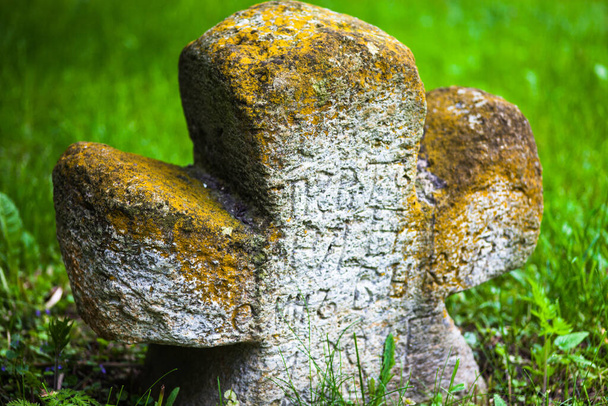 古い苔で成長した石の十字架に刻まれた古い教会のスラブ語の碑文。ウクライナのキエフ。閉じろ!. - 写真・画像