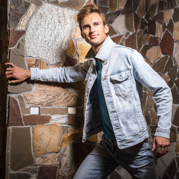 Young handsome man model against natural stone background. - Φωτογραφία, εικόνα