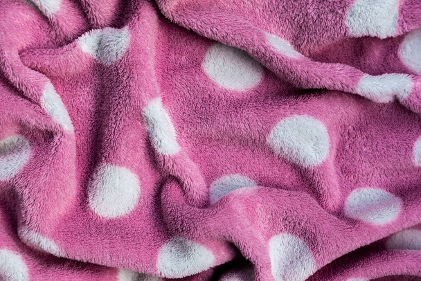 Рожевий ніжний м'який фон з хутра плюшевої гладкої тканини з білими колами. Текстура світло-червоного м'якого кремезного ковдру текстилю
. - Фото, зображення