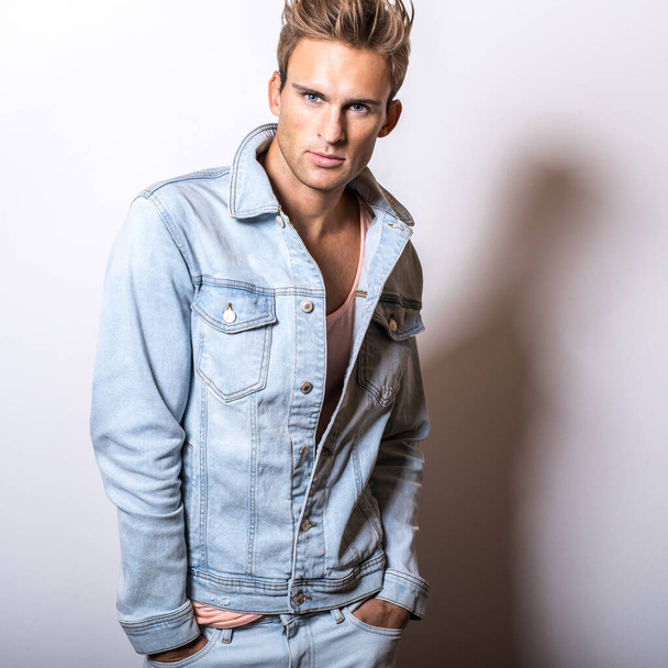 Handsome young man in jeans jacket pose in studio. - Foto, afbeelding