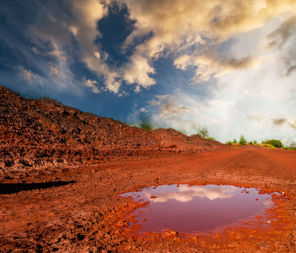 Dry red soil with puddle at sunset - Photo, Image