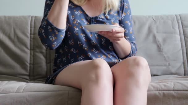 Unrecognizable woman in casual dress sitting on a sofa, coach and drinking hot coffe or tea, she is relaxing after doing home routine - Imágenes, Vídeo