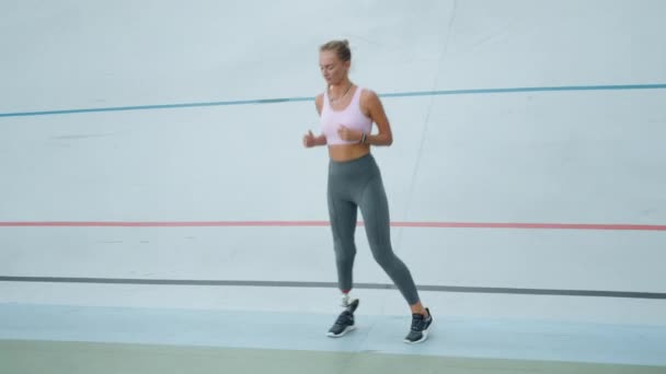 Vrouw met kunstmatige ledematen die zijwaarts springt in het stadion. Loopbaantraining buiten - Video