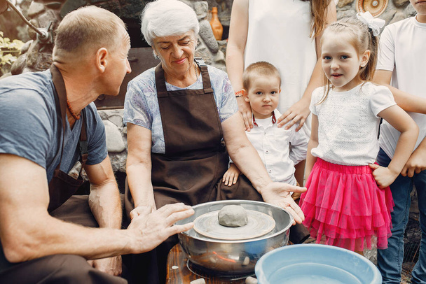 Grandparents with a grandchildren make jug in pottery - Foto, immagini