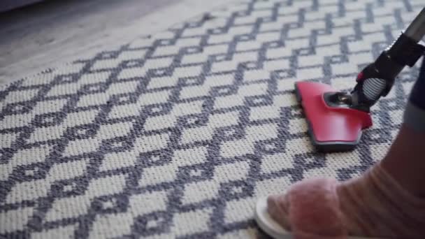 Egy fiatal nő porszívóval tisztítja a szőnyeget. - Felvétel, videó