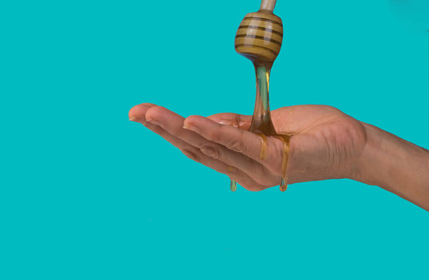 Main humaine pleine de miel isolé sur un fond bleu cyan
 - Photo, image