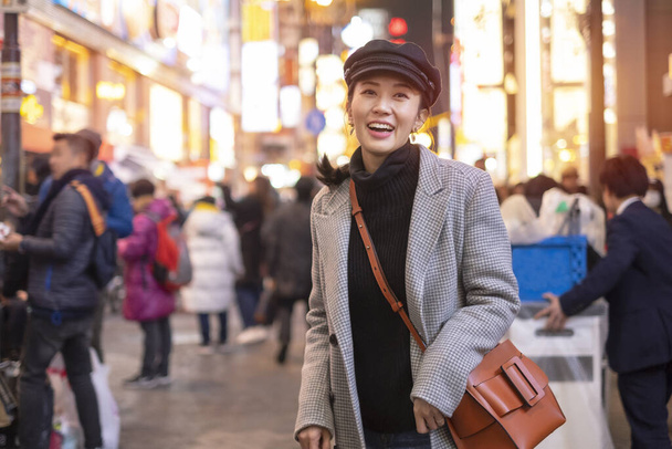 Улыбающаяся женщина-туристка во время прогулки в уличном торговом центре Сибуя в Токио, Япония
. - Фото, изображение