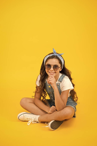 Fashion trend. Little fashionista. Cute small kid fashion girl. Summer outfit concept. Girl long curly hair sit relaxing. Fashion accessories. Carefree happy childhood. Modern clothing for teen - Photo, image