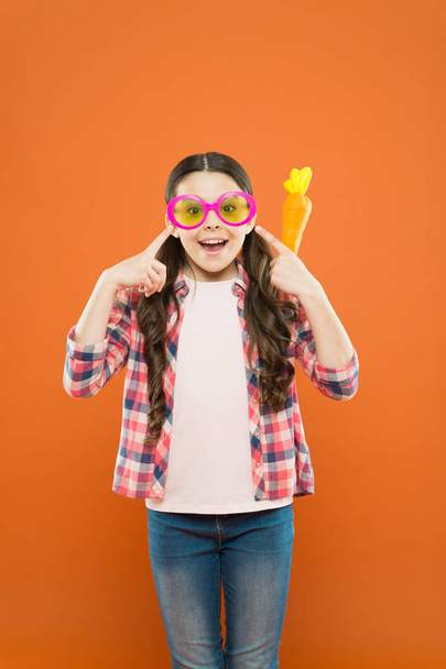 look at my glasses. she is ready for celebration. happy easter. Easter Egg Hunt. Easter eggs for holiday. child wearing party glasses on Easter day. Funny decoration. little girl hold carrot - Photo, Image