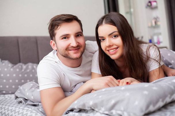 Happy sensual young couple lying in bed together - Photo, Image
