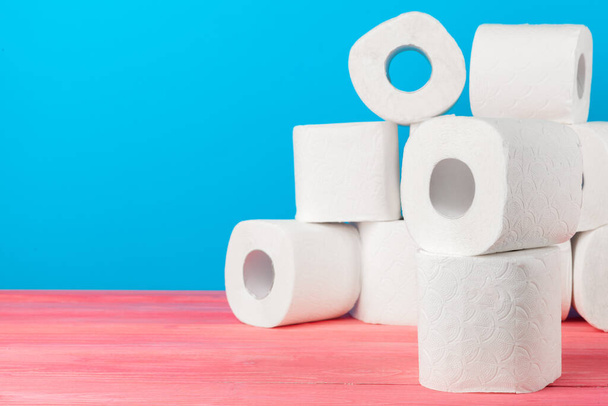 Toilet paper rolls stacked against blue background. Creative photo. - Foto, immagini