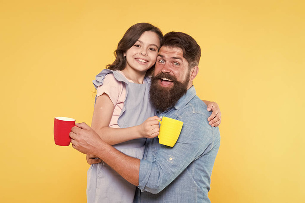 Drink water. Drink fresh juice. Breakfast concept. Good morning. Having coffee together. Lovely family tradition. Drinking tea. Bearded man and happy girl holding mugs. Father and daughter hot drink - Photo, Image