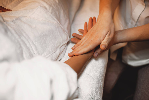 Experienced dermatologist is massaging clients hand after applying an anti aging cream - Φωτογραφία, εικόνα